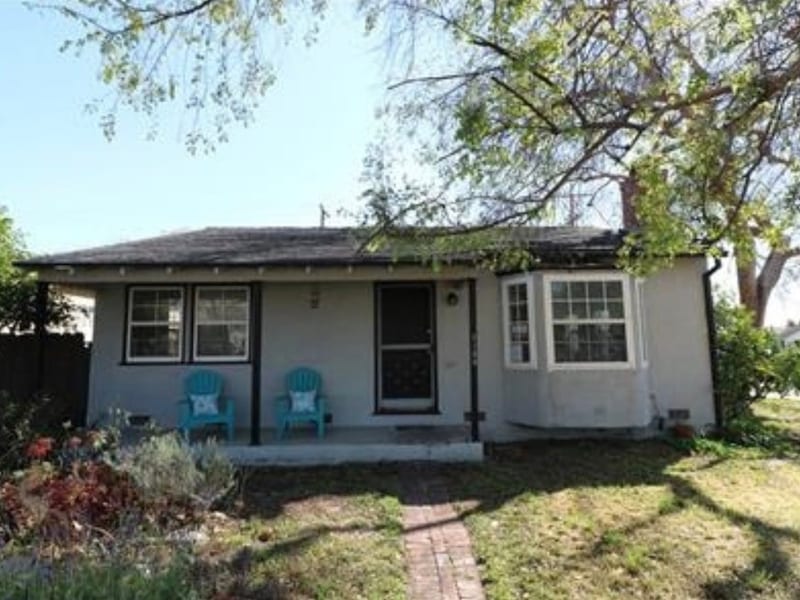 White cottage with blue chairs on front porch